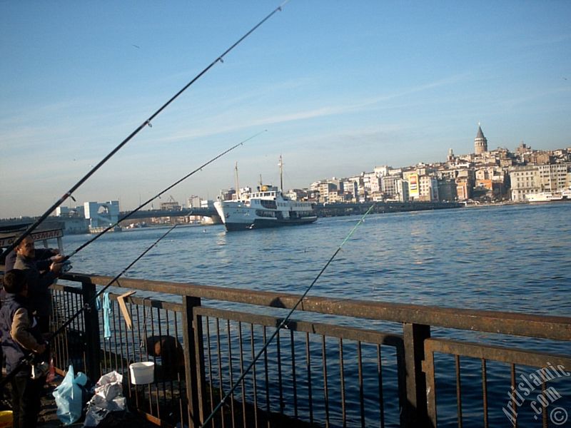 Emin�n� sahilinde bal�k tutanlar, iskeleye yana�an vapur, Yeni Galata K�pr�s� ve Galata Kulesi.

